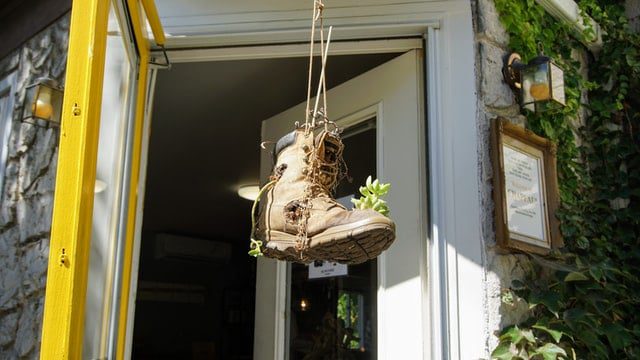 An old boot repurposed as a plant pot hanging outside the front door of a house