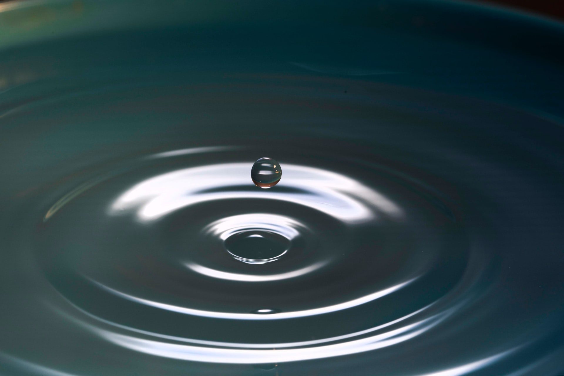 A single water drop causes a ripple in a still pond