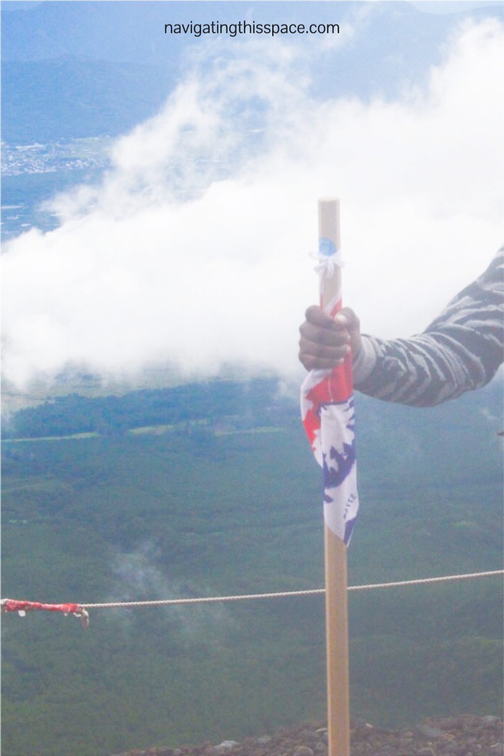 hand holding on to a hiking stick for support while hiking up Mt. Fuji