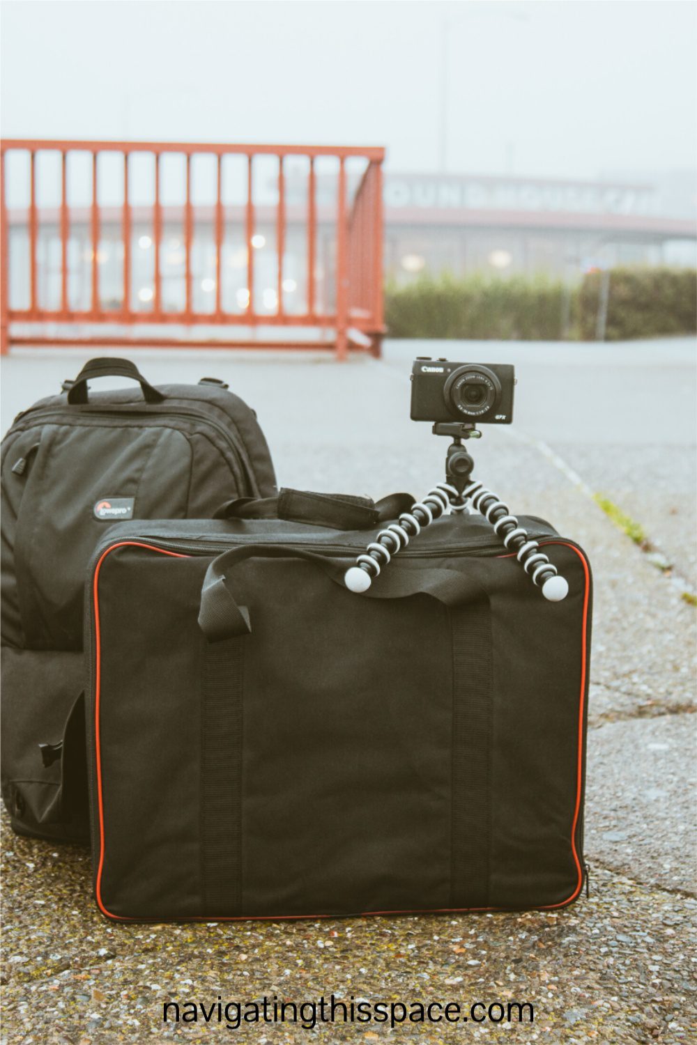 Two luggage bags and a camera on a mini tripod sitting on a pavement