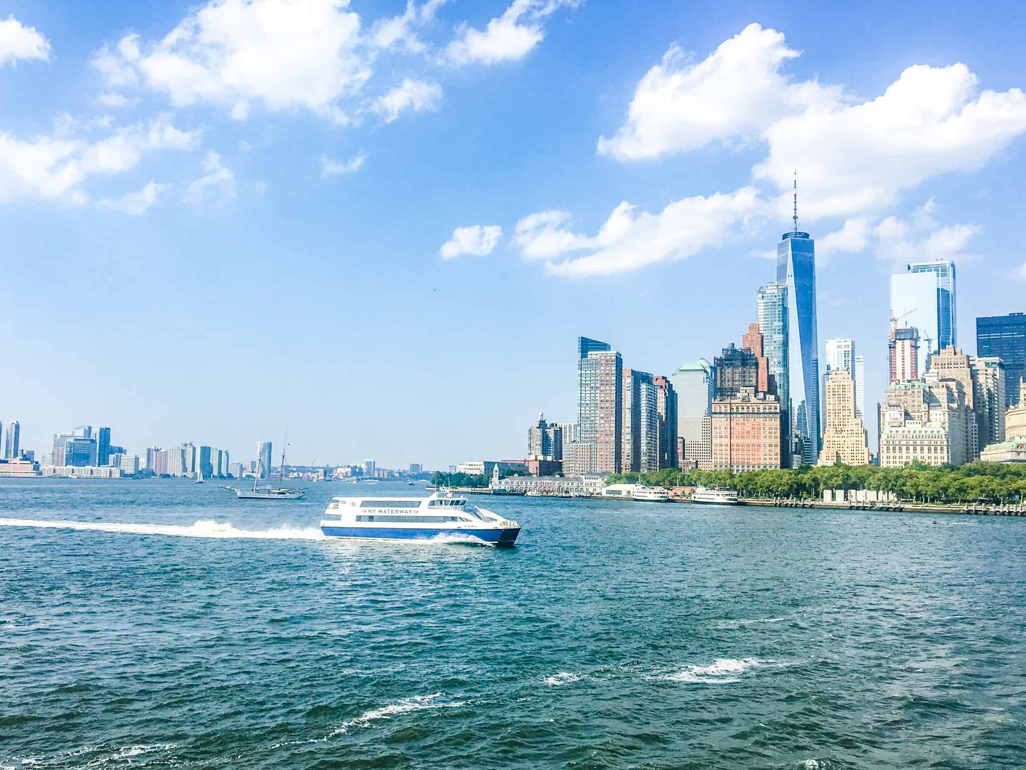 A ferry sailing across the Hudson river with New York City skyscrapers in the background