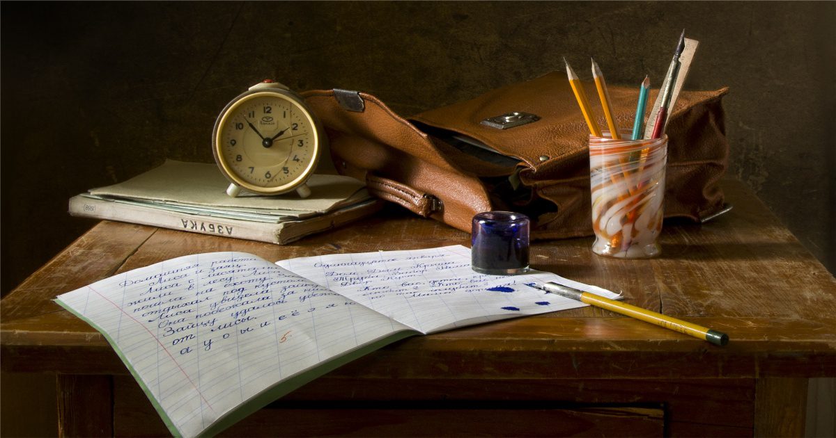 a table set up for a journal writing session with pens, pencils and a clock