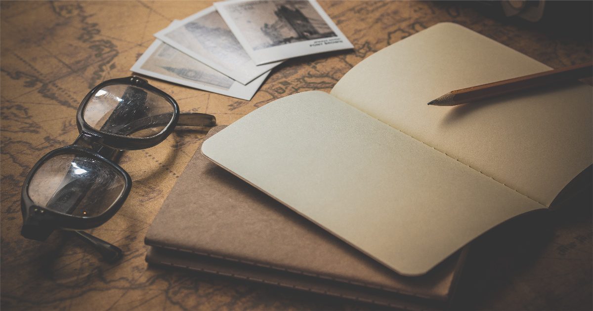 an open journal notebook with a reading glasses and polaroid photos laying around