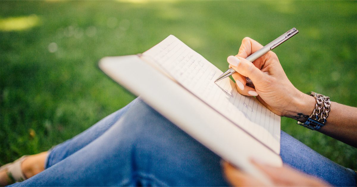 a figure writing in a journal in a park