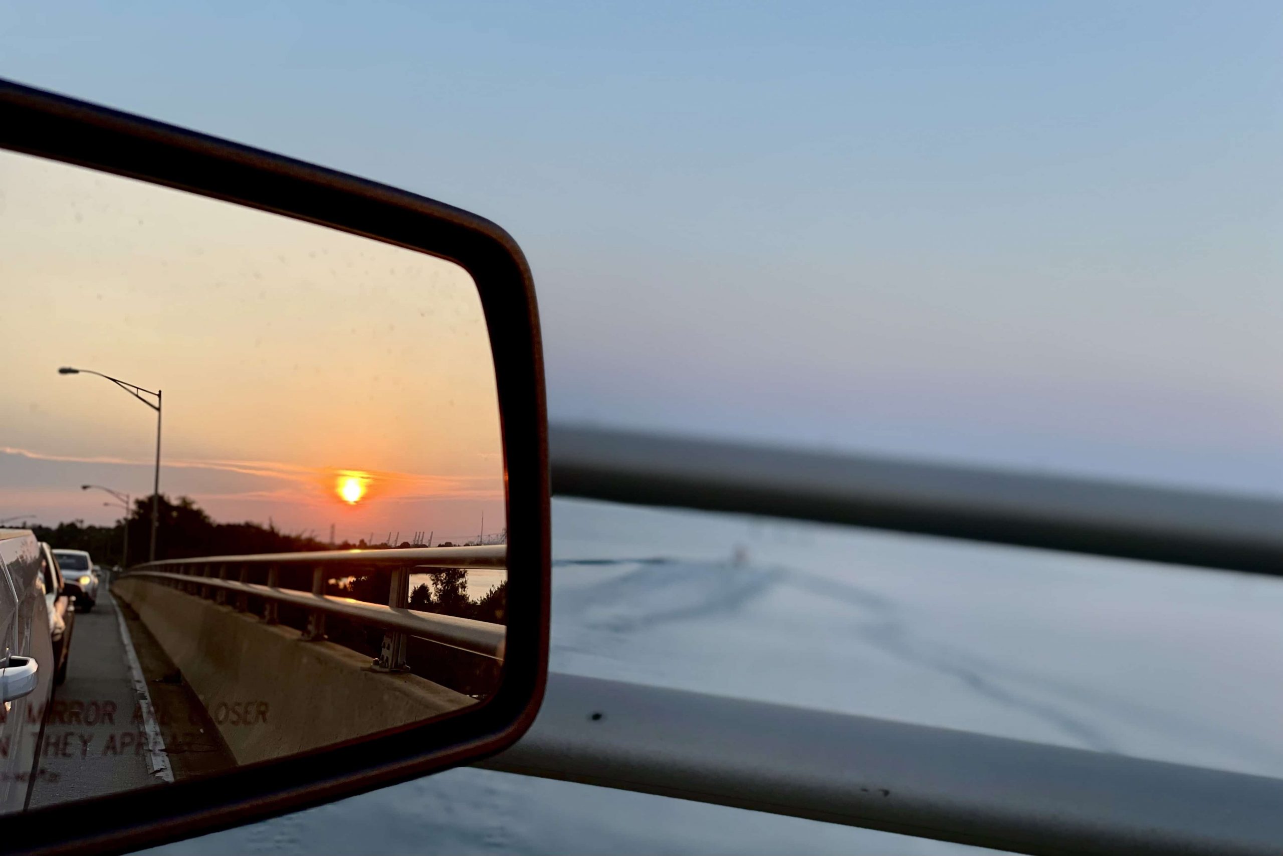 mirror on a car showing the reflection of a sunset