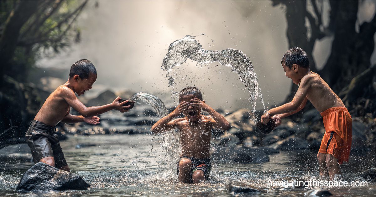 three kids playing in the river water