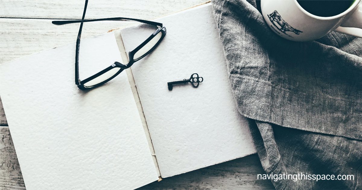 Blank open notebook with a small key and a glasses