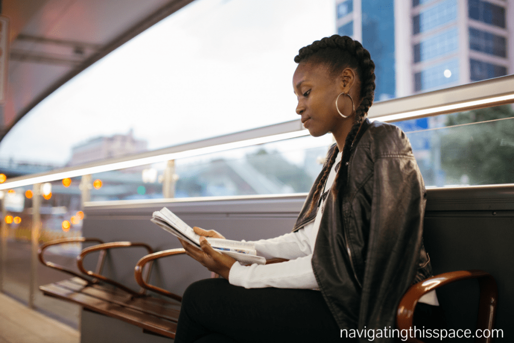 A black woman sitting down on a chair reading a book