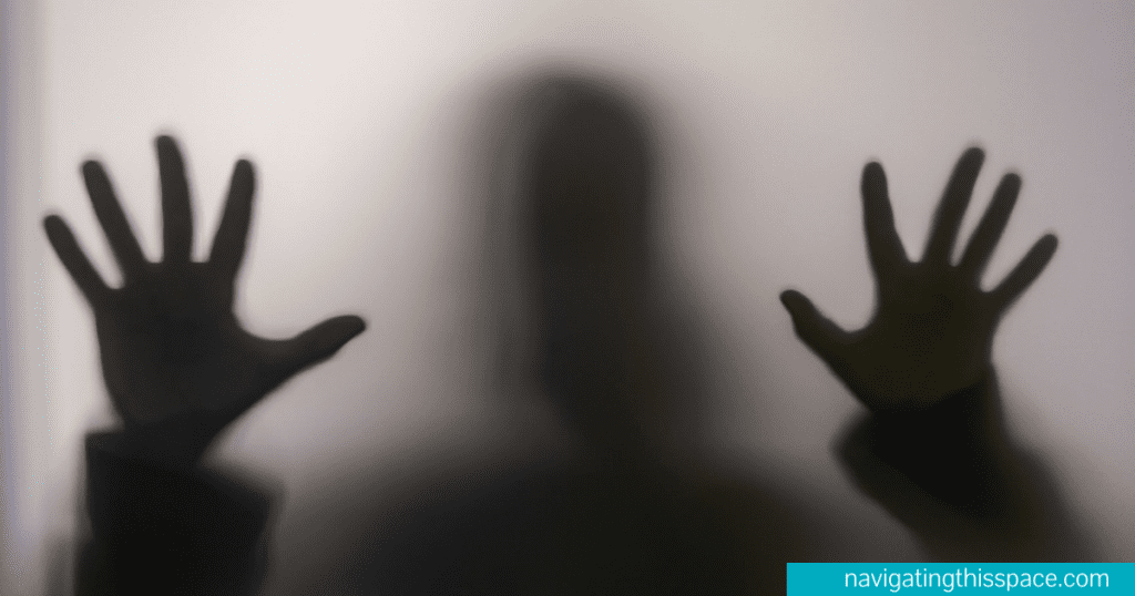 A silhouette hand against a glass wall signifying fear