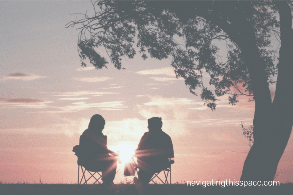 Two Silhouette Images under a tree at sunset discussing