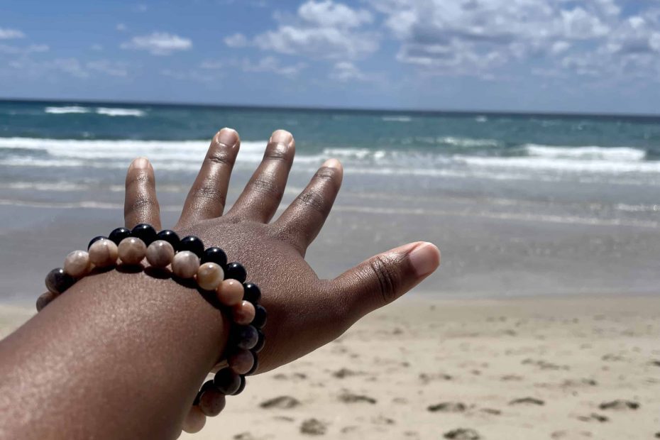 a hand at the beach reaching towards the water