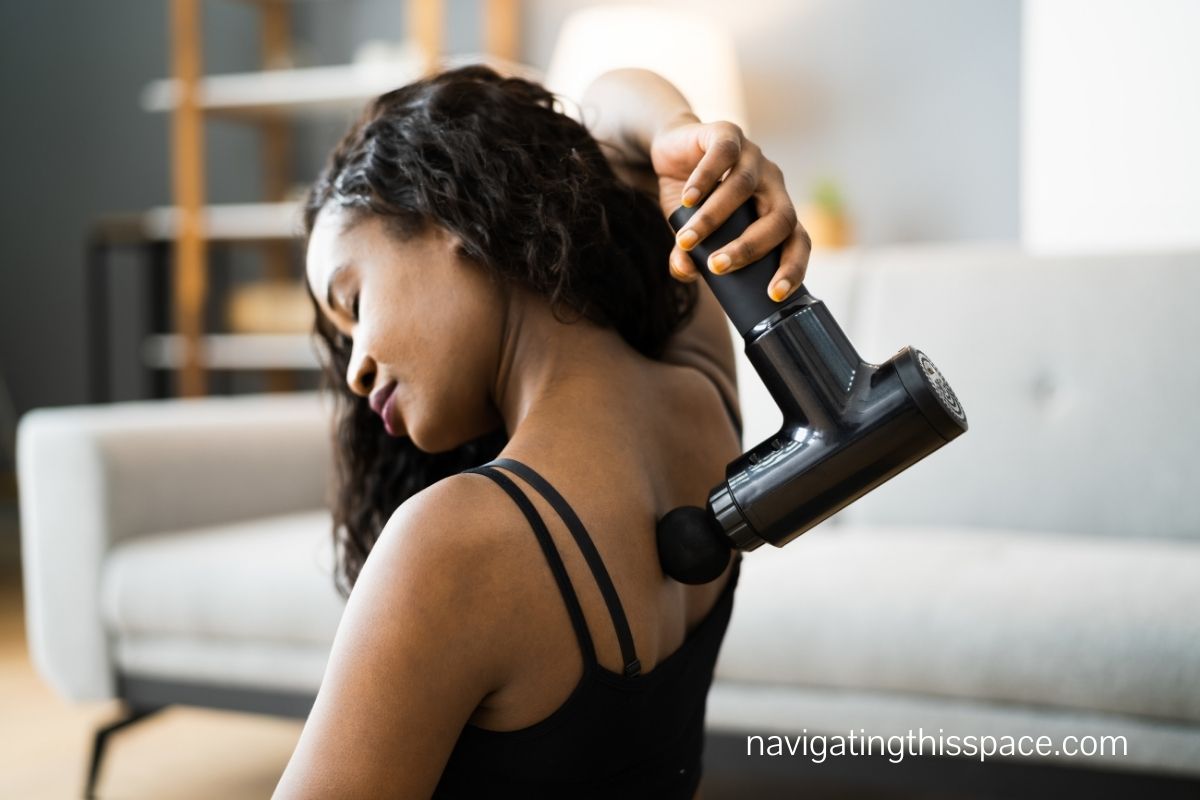 an african woman using a massage gun on her back